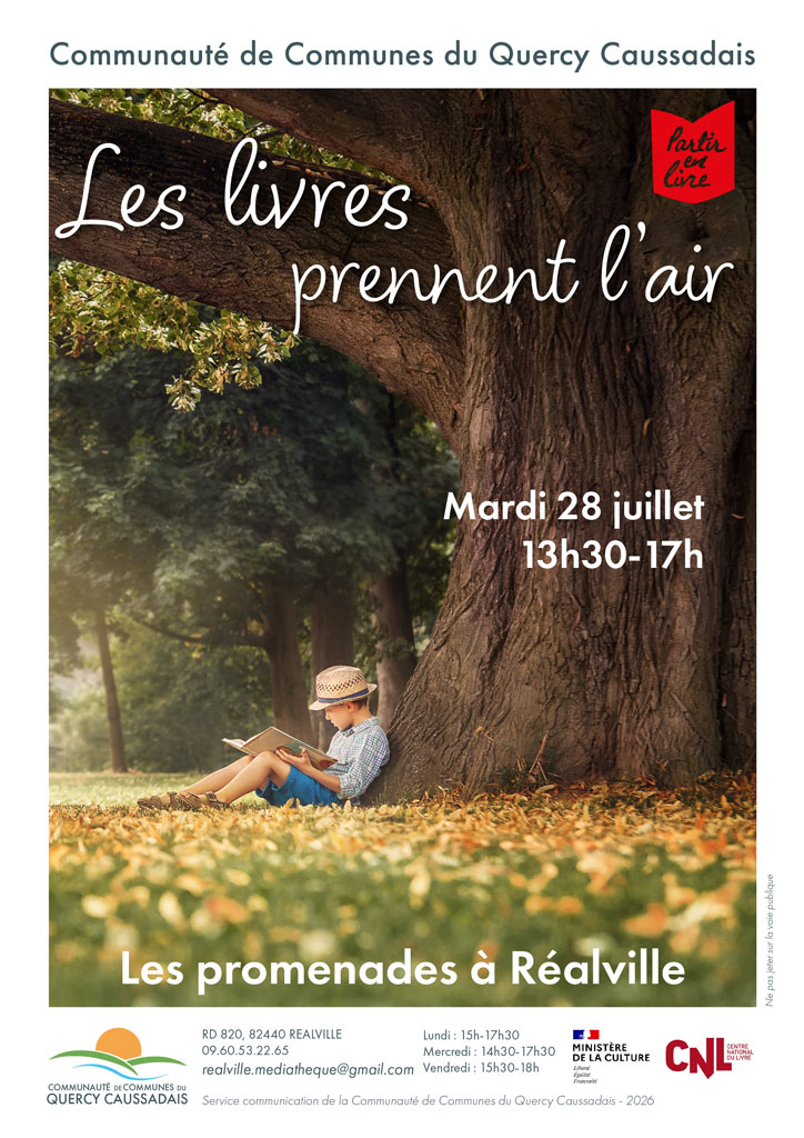 Jeune garçon qui lit sous un arbre assis dans l'herbe